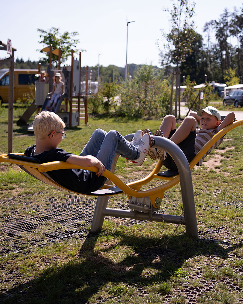 Zwei Kinder spielen auf einer inklusiven Wippe Vippy auf einem Spielplatz.